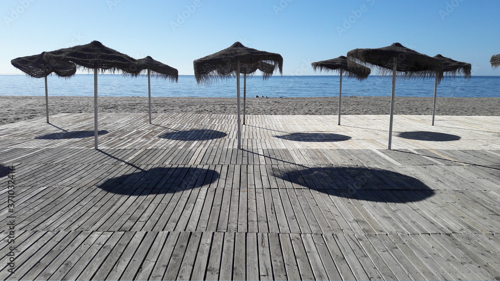Parasoles dando sombra en un suelo de madera junto al mar