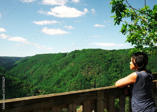 An Afro-Asian woman seen from behind is admiring the mountain scenery. During the holidays, tourists like to take a break to admire the natural landscape