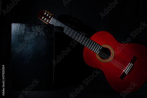Photography spanish classical red guitar with flamenco cajon on a black background