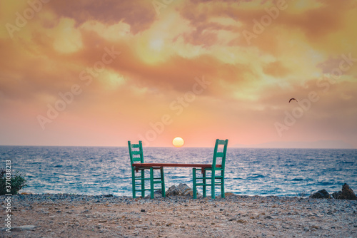 Chairs reflection at sunset near traditional pictorial coastal fishing village of Milatos, Crete, Greece. © gatsi