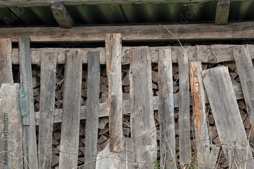 Old barn with firewood. The woodpile is closed by a fence made of old gray planks. Background. Texture.