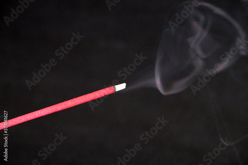 smoking incense stick on black background close up
