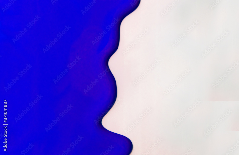 Dark blue paint spreads on a white background. Copy space.