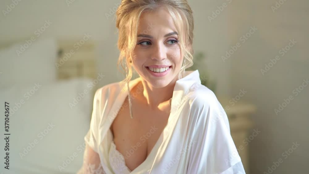 beautiful blonde bride in a silk robe on the bed.