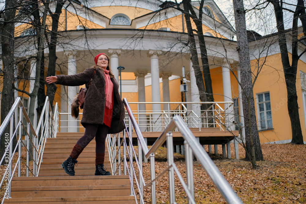 Young woman on the background of a historic building in an autumn park