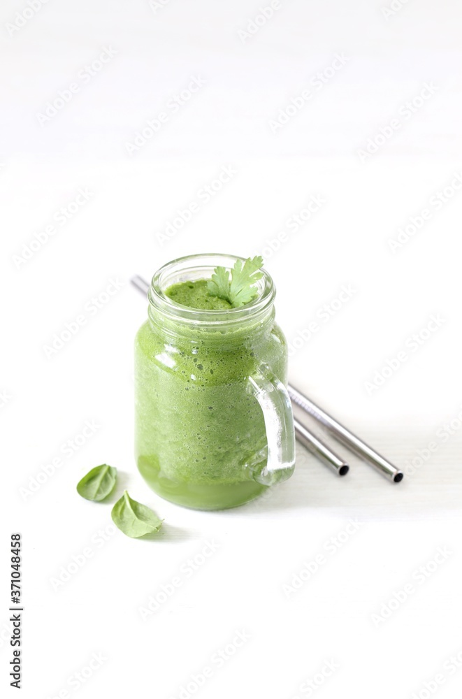 Green smoothie with parsley and spinach with a metall straw on a light background Green smoothie with parsley and spinach with a metall straw on a light background
