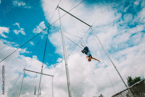 kid having swing on a high flying trapeze, boy learning acrobatic