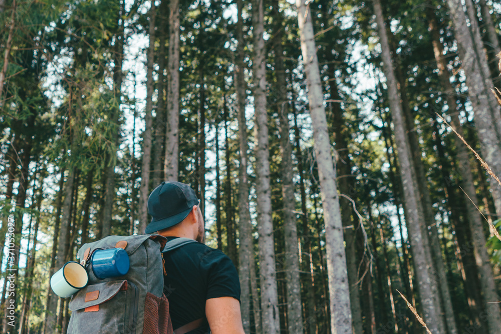 man with backpack walking by stone stairs that leads to the forest