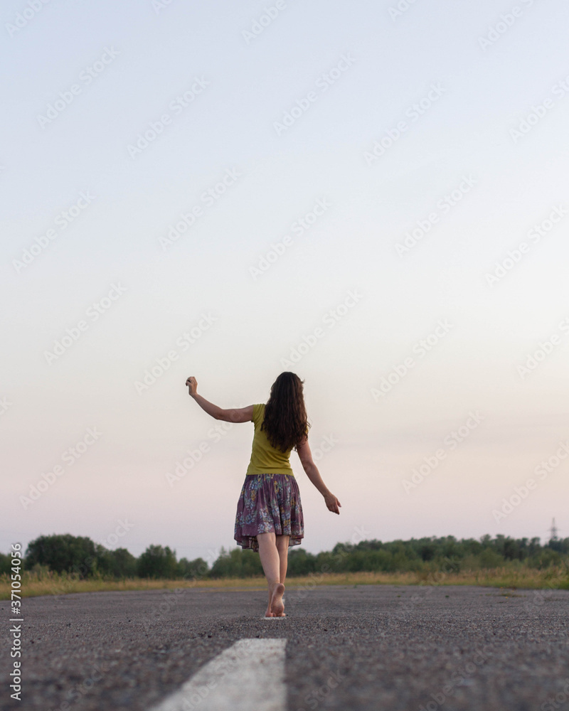 Fototapeta premium The girl leaves on the road barefoot