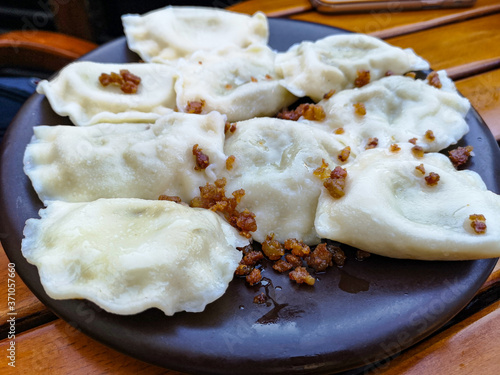 Dumplings with greaves on a dark plate on a wooden table.