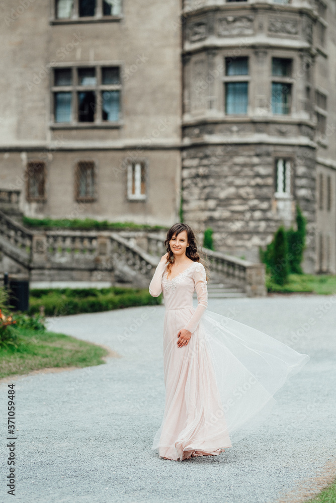 A girl in a light pink dress against the background of a medieva castle