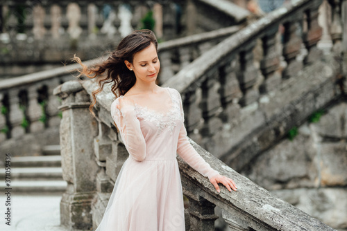 A girl in a light pink dress against the background of a medieva castle