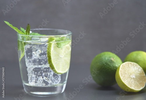Side view colorful image of glass of lemonade or gin tonic with lemon or lime. Copy space fort text.