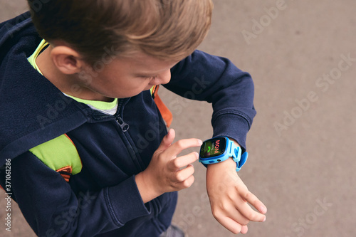 Wearable kids baby  calls mom and location tracking with touch screen and voice service, blue multicolored electronic gadget with rubber wristband for children. Close up boy with copy space. Time cloc photo