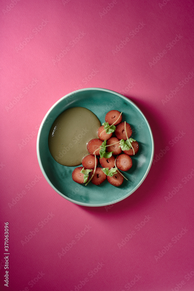 Erdbeeren Dessert mit grünem Salat und Sonnenblumenkernen auf türkisem Teller mit pinkem Untergrund Erdbeeren Dessert mit grünem Salat und Sonnenblumenkernen auf türkisem Teller mit pinkem Untergrund