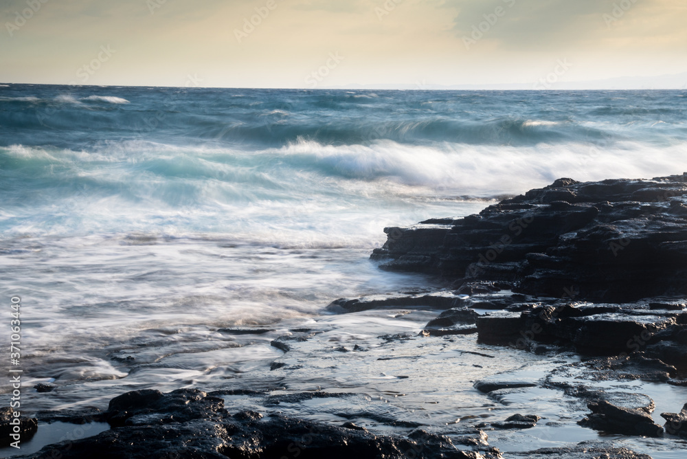 Fototapeta premium Splashing stormy windy sea waves on a rocky seashore