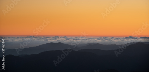 Colourful sunset with orange color above the clouds and the mountains.