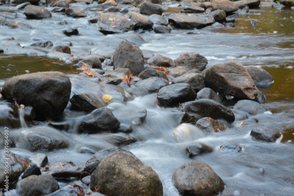Water Flowing Over Rocks in Autumn with Leaves in Water Water Flowing Over Rocks in Autumn with Leaves in Water