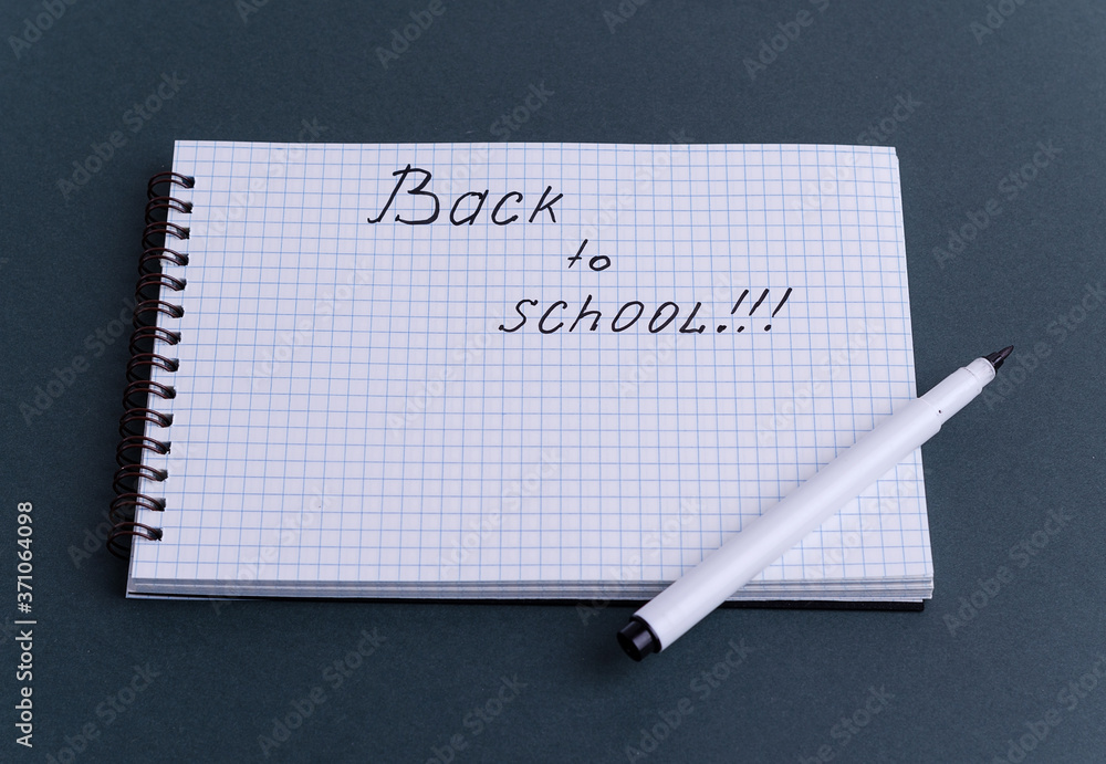 A checkered notebook lies on a dark background with the words A checkered notebook lies on a dark background with the words
