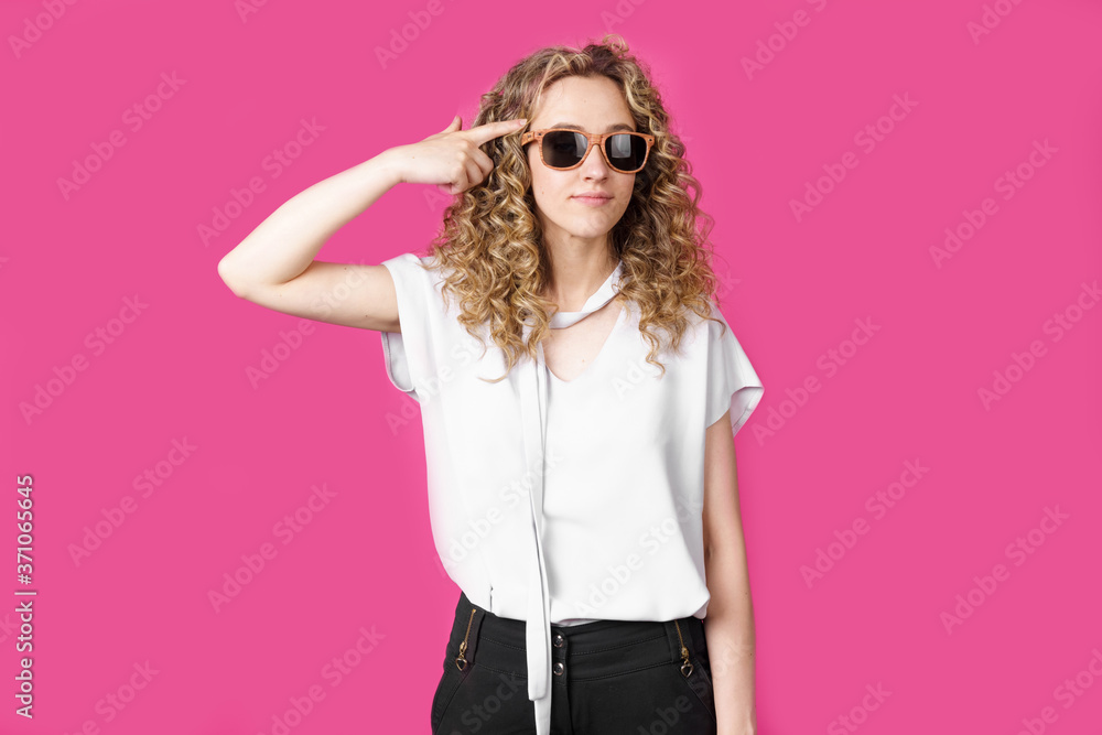 A young woman with glasses put her finger to her temple as a pistol. Female portrait. A young woman with glasses put her finger to her temple as a pistol. Female portrait.