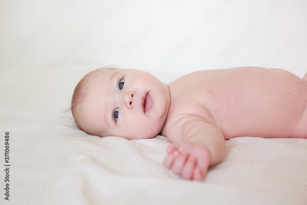 small child, baby lies on his stomach and smiles. On a white background. Newborn baby. three months old baby. A baby of European appearance. selective focus small child, baby lies on his stomach and smiles. On a white background. Newborn baby. three months old baby. A baby of European appearance. selective focus