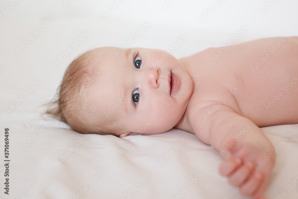 small child, baby lies on his stomach and smiles. On a white background. Newborn baby. three months old baby. A baby of European appearance. selective focus small child, baby lies on his stomach and smiles. On a white background. Newborn baby. three months old baby. A baby of European appearance. selective focus