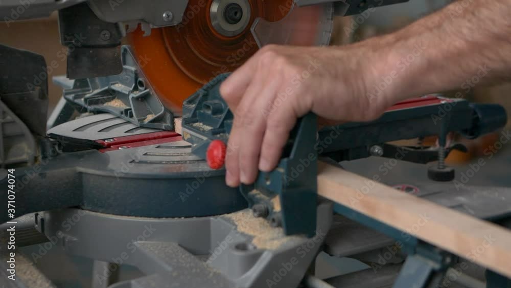 A carpenter works on a circular electric saw. A close-up of the hands of a worker and machine parts. Slow motion footage. A carpenter works on a circular electric saw. A close-up of the hands of a worker and machine parts. Slow motion footage.