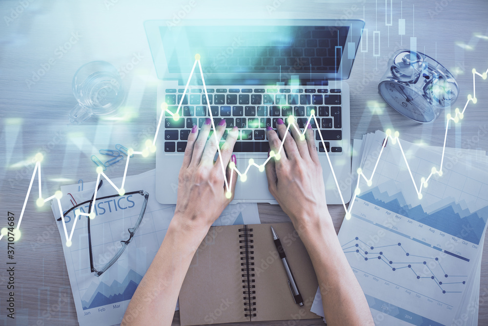 Double exposure of woman hands working on computer and forex graph hologram drawing. Top View. Financial analysis concept. Double exposure of woman hands working on computer and forex graph hologram drawing. Top View. Financial analysis concept.