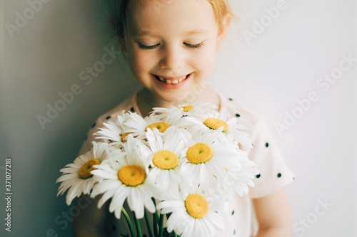 close up portrait of a happy little girl with flowers. Pretty little girl with chamomile. Girl with a beautifull blue eyes.