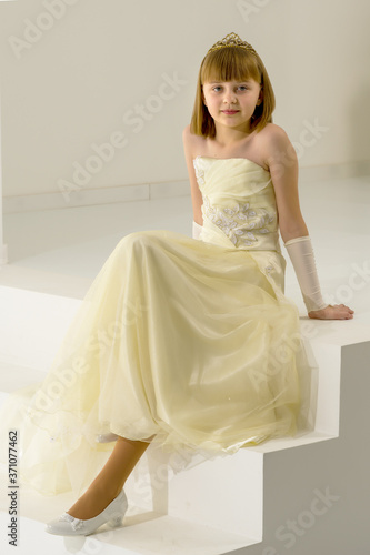 Beautiful little girl is sitting on the white staircase.