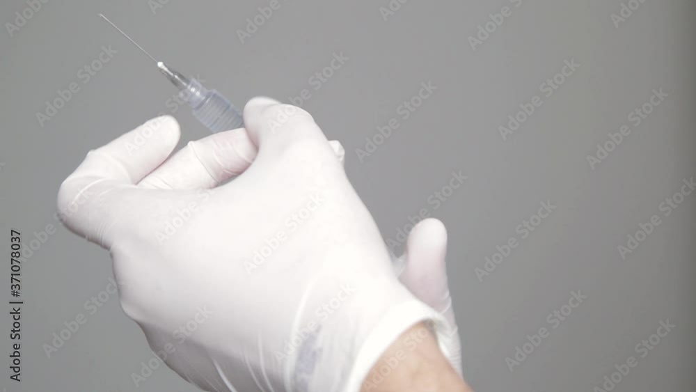 hand in glove holding syringe hand in glove holding syringe