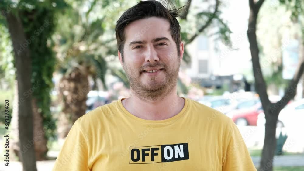 Handsome young man looking at camera. A young man smiles and looks at the camera. Portrait of a happy handsome young man on a city street. Handsome young man looking at camera. A young man smiles and looks at the camera. Portrait of a happy handsome young man on a city street.