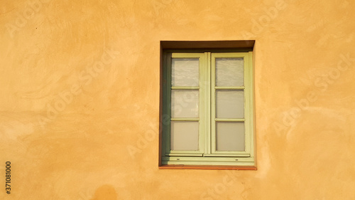 Sonnenbeschienene Hauswand, gelber Putz, Sprossenfenster