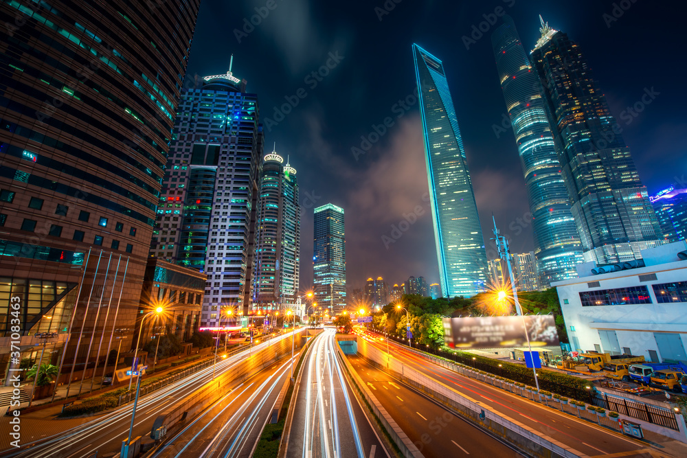 View of Lujiazui Business district skyscraper with traffic in street at night in Shanghai, China. Asian tourism, modern city life, or business finance and economy concept