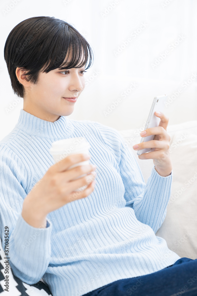 部屋でスマホを見る女性 部屋でスマホを見る女性