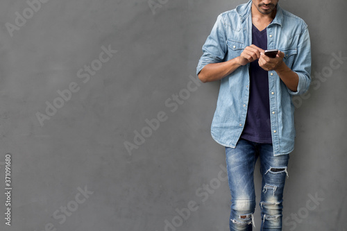 Happy young man using smartphone with social media application with copy space wall background
