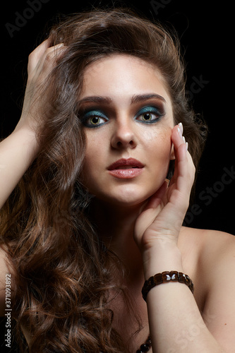 Beauty portrait of young woman. Brunette girl with long hair and evening female makeup on black background