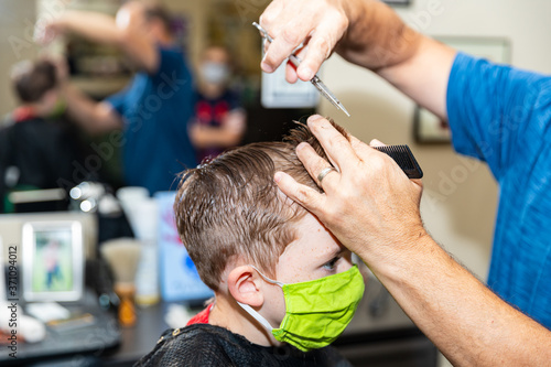 Boy gets haircut during pandemic while wearing face mask