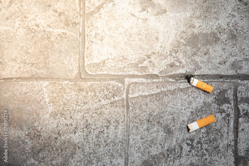 Close up and top view of the finished cigarette butts thrown on concrete floor of the pavement in urban city shows bad habit in environment pollution and risk danger for people health