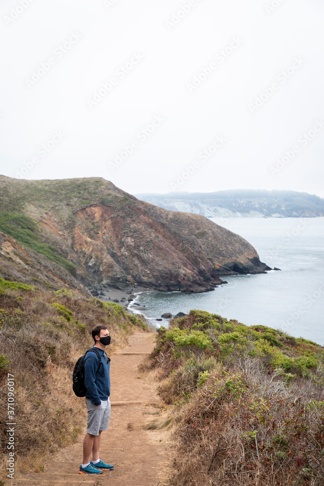 Man wearing face mask while hiking trail along Northern California coast Man wearing face mask while hiking trail along Northern California coast