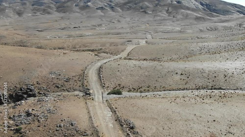 Road crossing arid desert of Morocco with mountains in background. Aerial top view photo