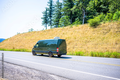 Compact cargo dark gray mini van running for delivery on the winding summery road