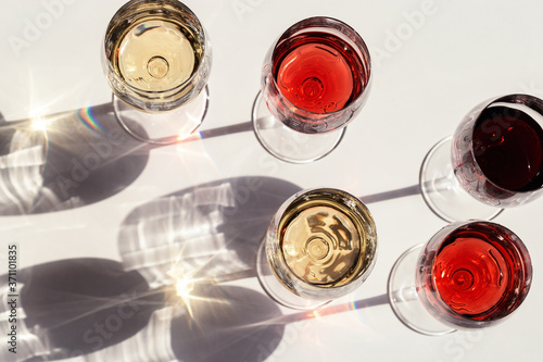 Red, rose and white wine top view in sunlight. Dark shadows