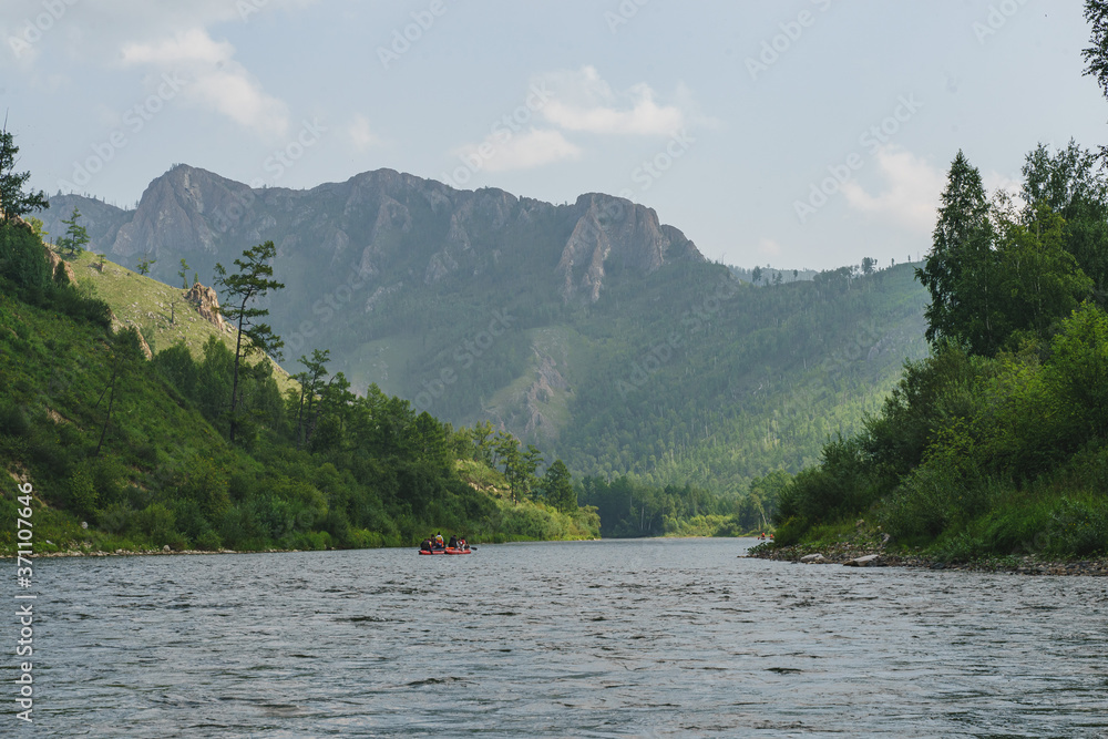 White Iyus river among hills and rock massifs. People float down the river on catamarans. Russia, Khakassia.