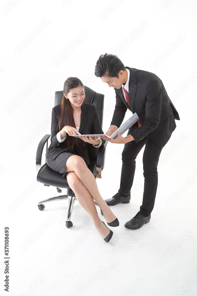 South East Asian young Chinese man woman wearing formal business office ware on white background standing sitting on office chair talk discuss file paper project South East Asian young Chinese man woman wearing formal business office ware on white background standing sitting on office chair talk discuss file paper project
