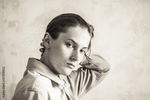 Tomboy straightens his hair. Tomboy in a denim jacket. Sepia portrait
