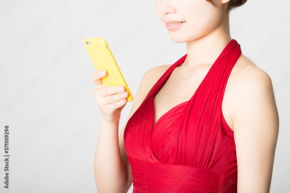 スマートフォンを操作するドレス姿の女性 スマートフォンを操作するドレス姿の女性