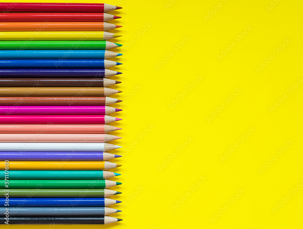 Colored pencils on yellow background with empty space  for text on one side 