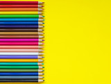Colored pencils on yellow background with empty space  for text on one side 