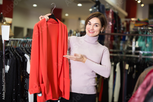 Happy female customer deciding on jersey cardigan in women cloths shop